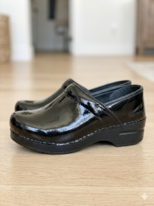 Black patent leather slip-on loafer with a thick platform sole on a wooden floor.