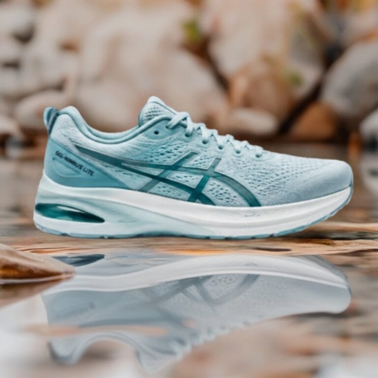 Light blue ASICS Gel-Nimbus Lite running shoe shown from the side with a white sole and breathable upper, reflected in water.