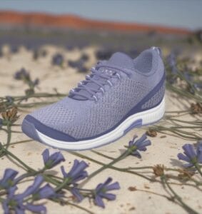 Lavender running shoe on sandy ground with purple flowers in the foreground.