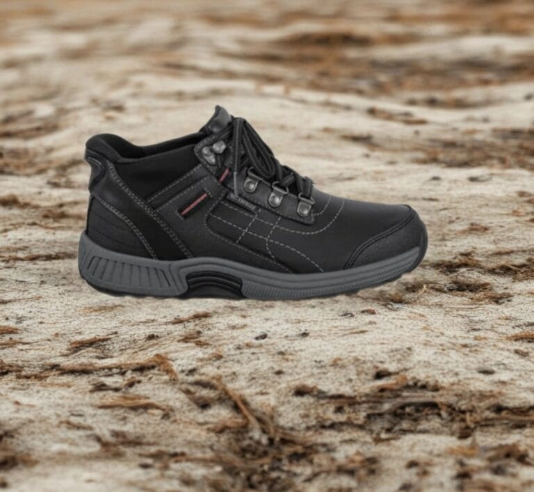 Black hiking shoe on a rugged, sandy ground; sturdy sole and laces visible, outdoors scenario