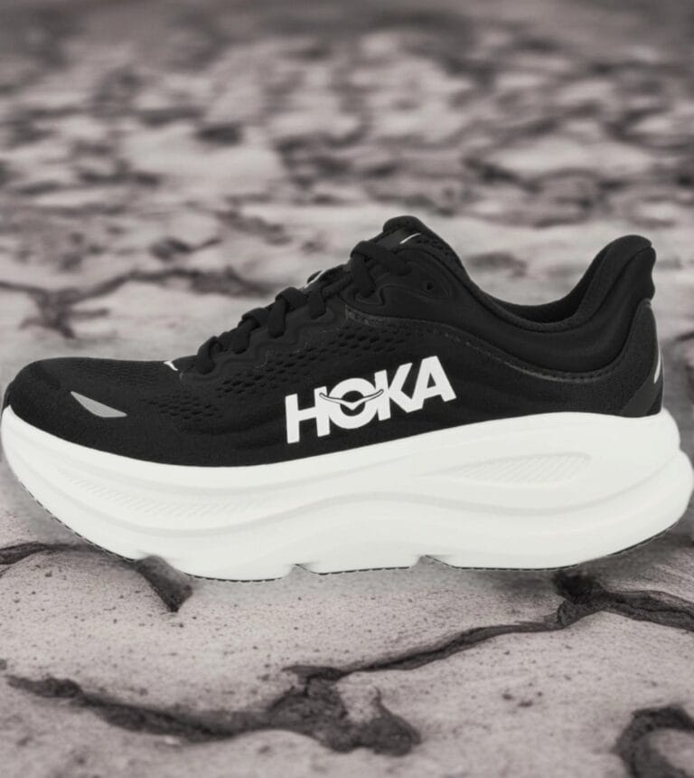 Black HOKA running shoe with a thick white sole on a rocky surface, side view