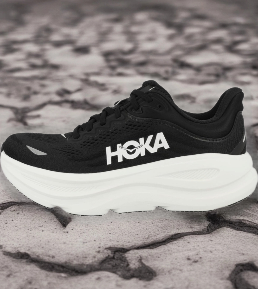 Bazaart_20260724_031528_925 - Rejuva Sole™ Black HOKA running shoe with a thick white sole on a rocky surface, side view