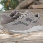 Grey athletic sneakers on a wooden surface, close-up of the side and laces, casual outdoor footwear